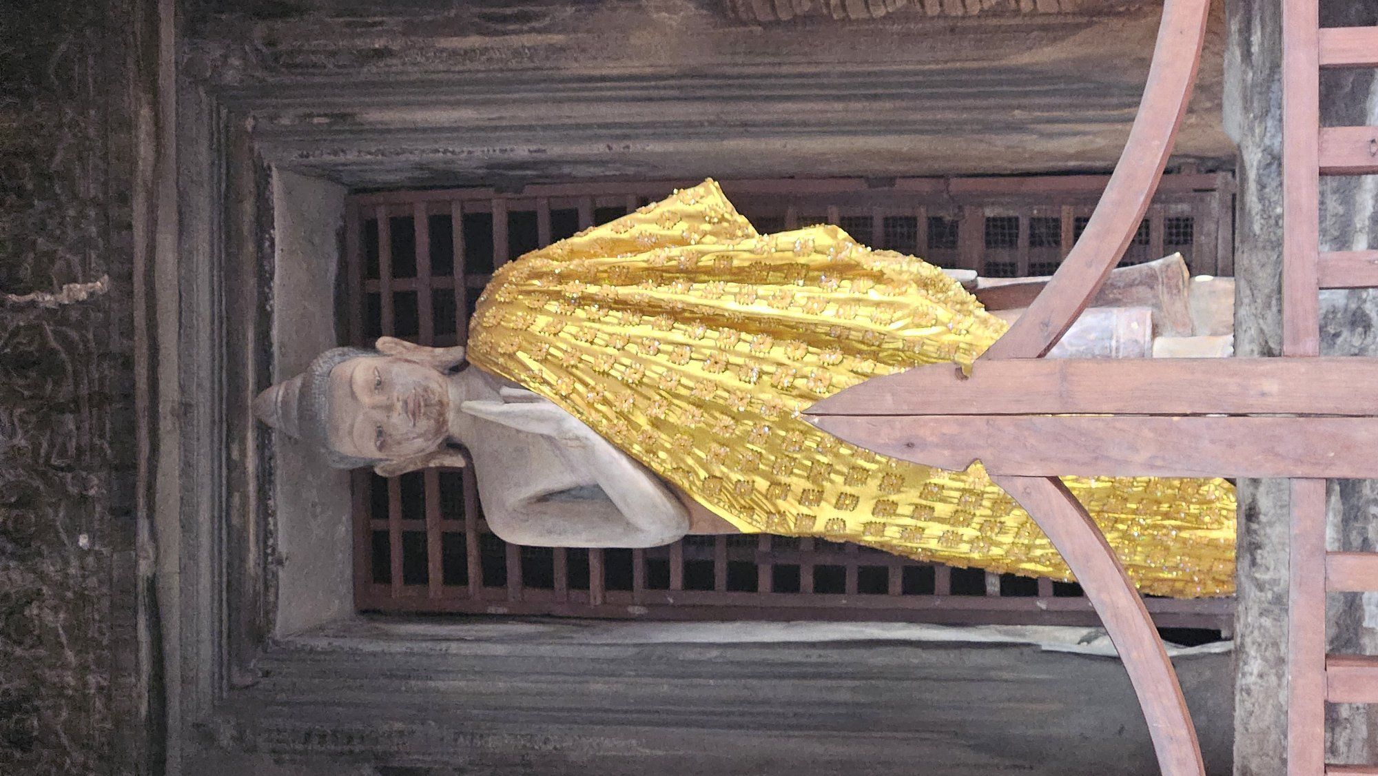 A saffron-robed Buddha standing in a window of Angkor Wat's inner gallery