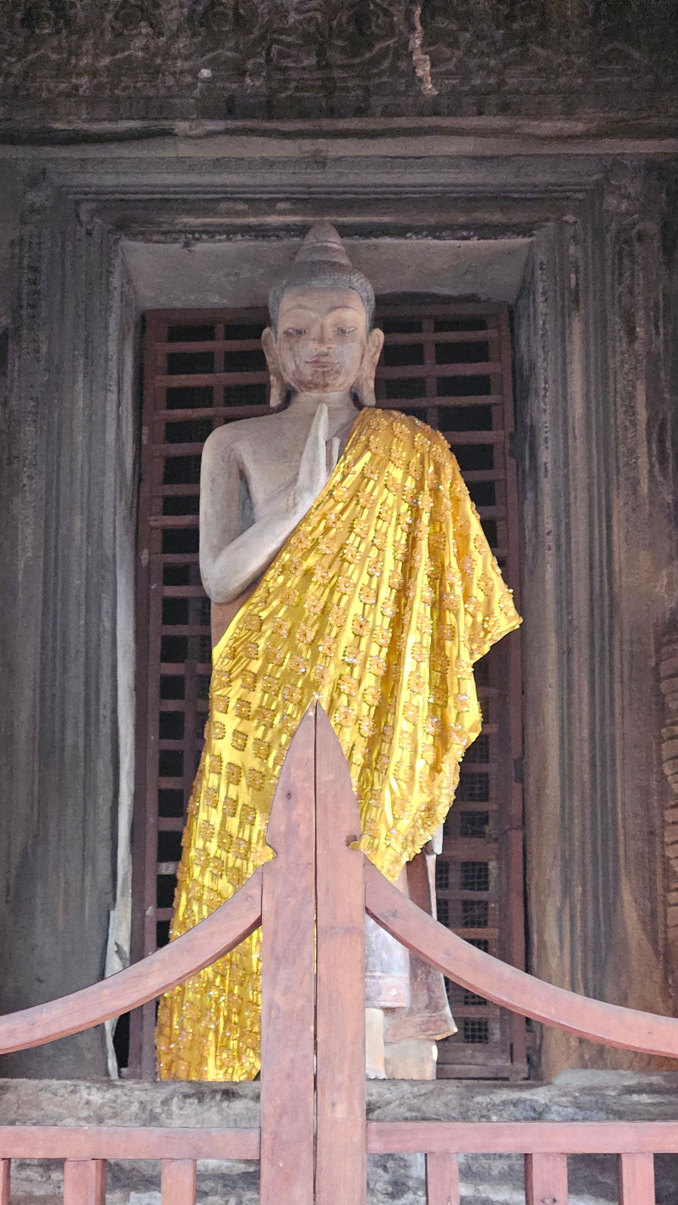 A saffron-robed Buddha standing in a window of Angkor Wat's inner gallery