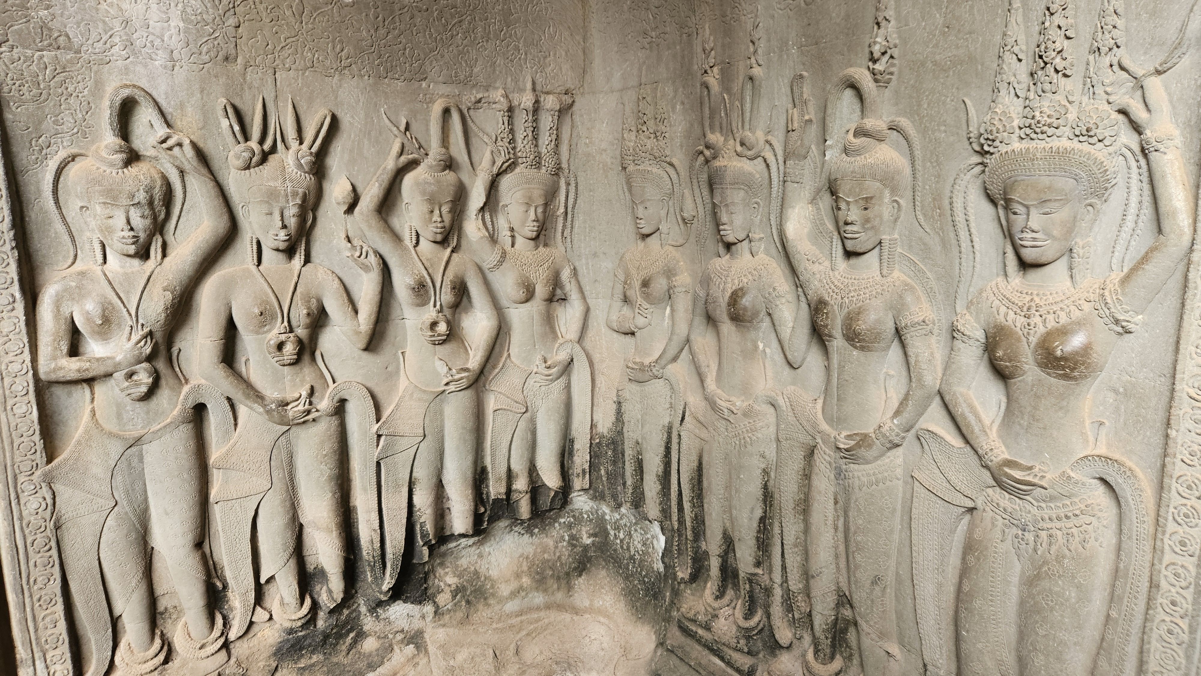 A row of carved apsara dancers on a wall of Angkor Wat