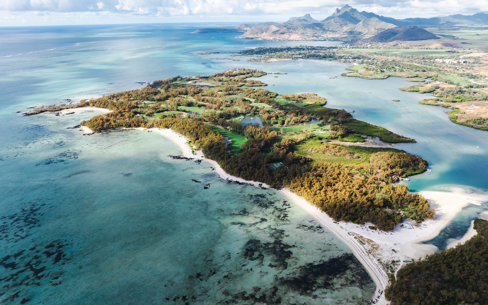 A calm turquoise lagoon fringed by palm trees and white sand on the east coast of Mauritius near Ile aux Cerfs