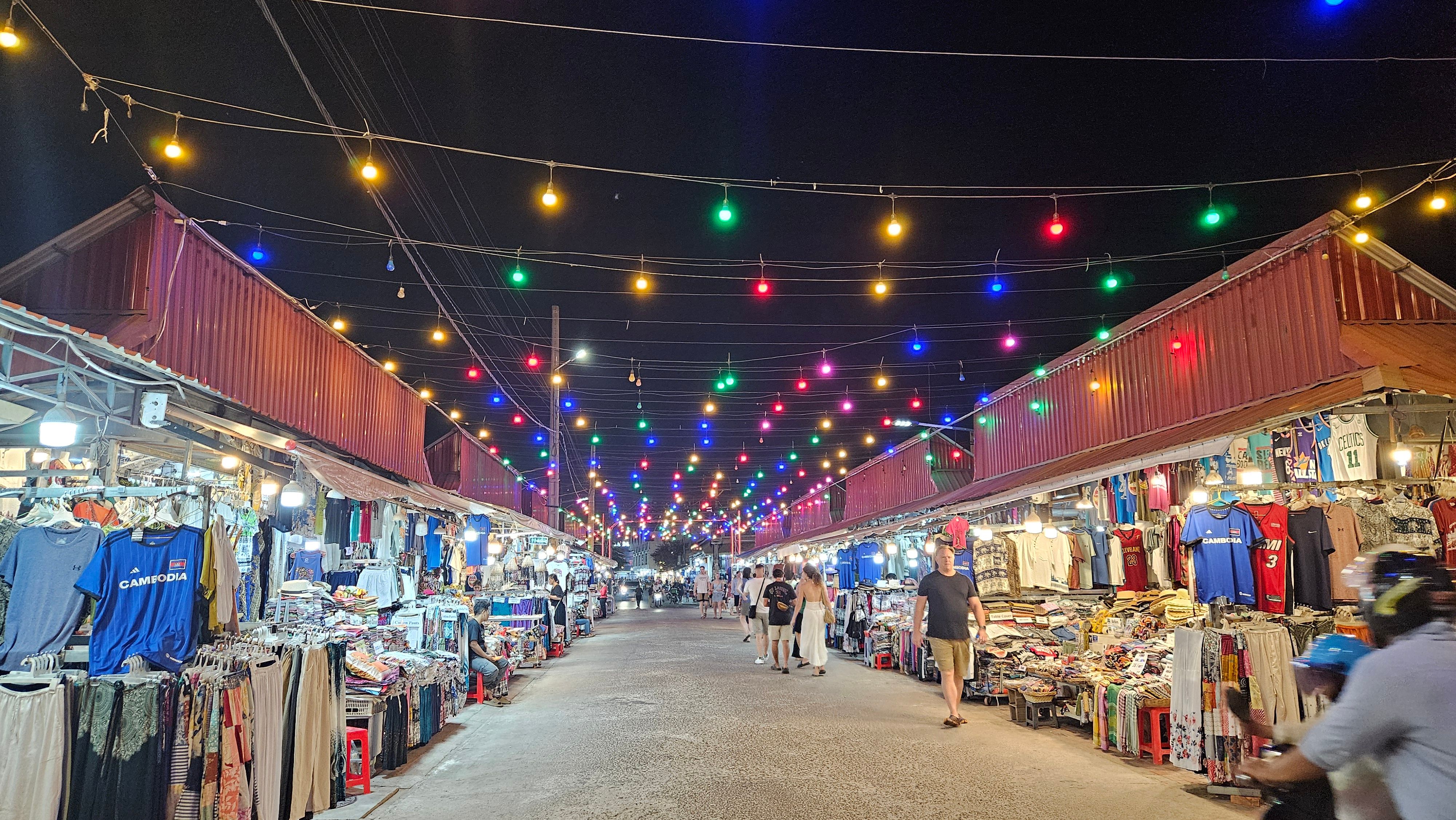 A string-lit night market alley lined with stalls in Siem Reap
