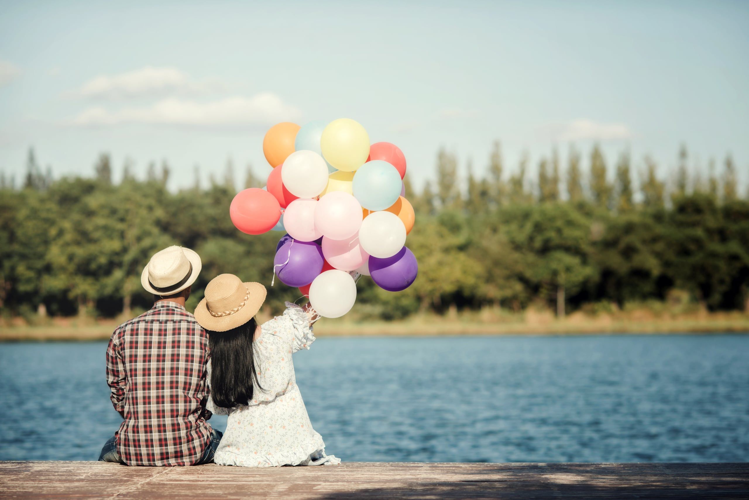 A couple celebrating by a lake with balloons